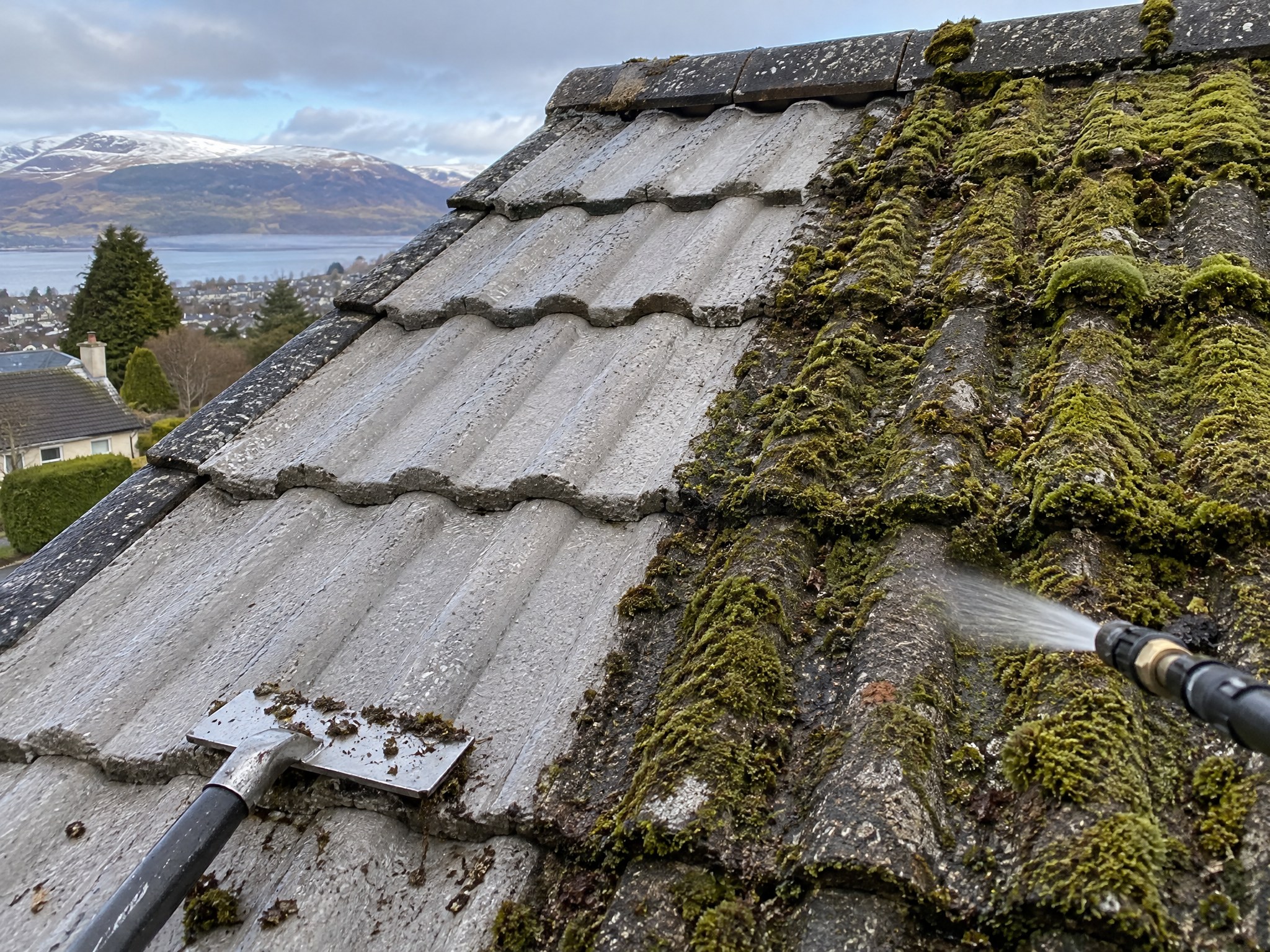 Moss being removed from concrete roof tiles on a UK home